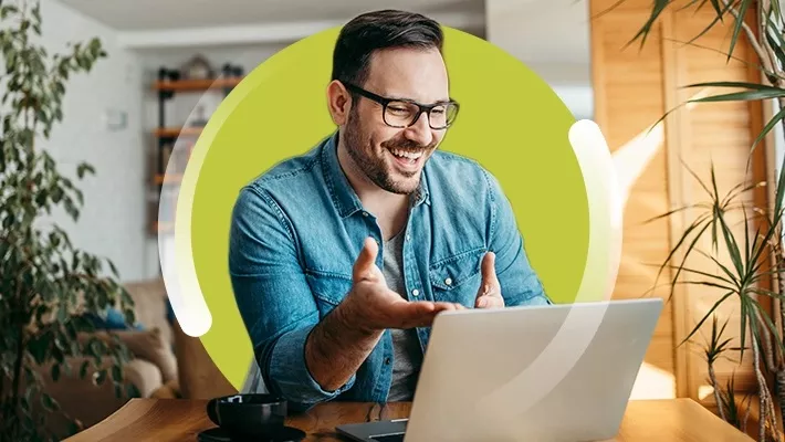 Descrição de imagem: homem sorrindo de frente para o notebook.